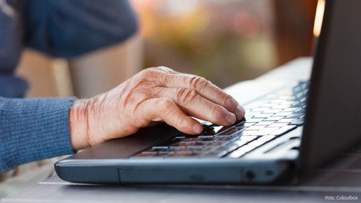 Das Foto zeigt die Hand eines Seniors an der Computertastatur.